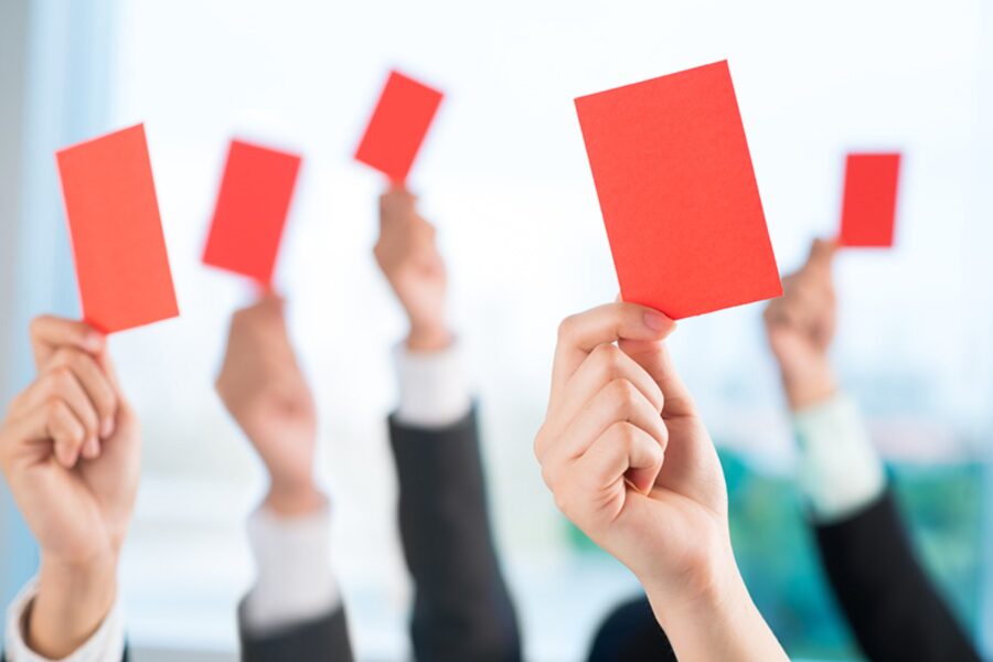 Several hands holding red cards.