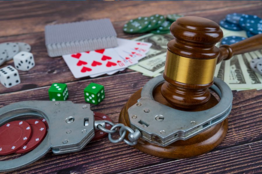 a gavel inside handcuffs with cards, dice and chips in view.