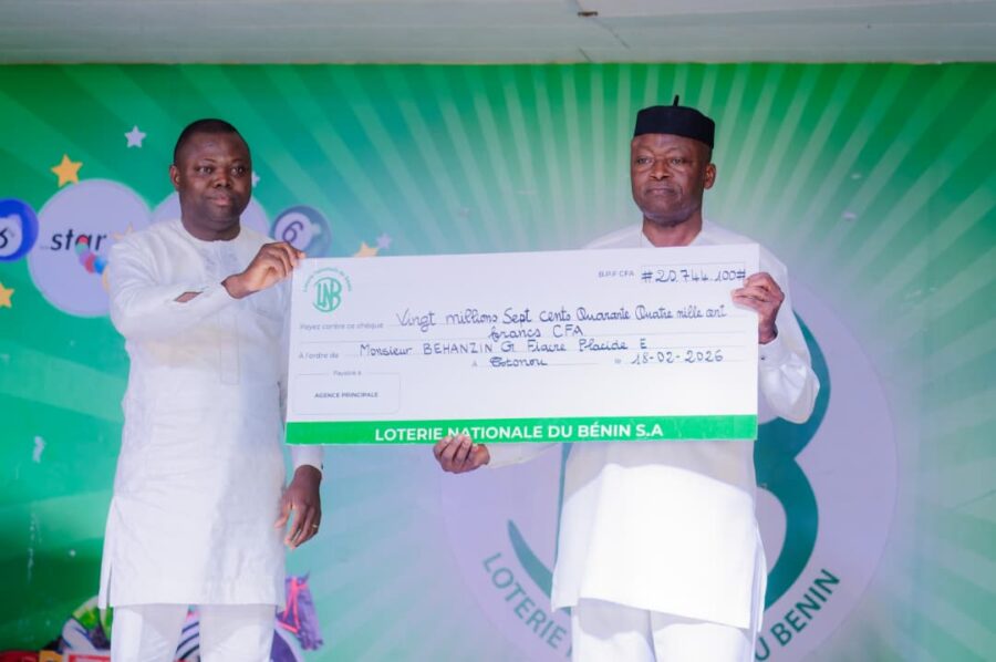 Winner Behanzin Eude (right) receives his prize cheque during a public ceremony organised by the National Lottery of Benin. 