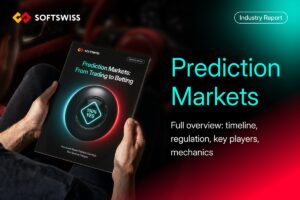 A promotional graphic for a SOFTSWISS Industry Report. On the left, a man seen from an over-the-shoulder angle holds a booklet titled ‘Prediction Markets: From Trading to Betting’. The booklet’s cover displays a central graphic of a black sphere encircled by a glowing blue and red ring with a teal diamond containing the text ‘100% YES’. On the right, large teal text reads ‘Prediction Markets’, followed by the white subheading ‘Full overview: timeline, regulation, key players, mechanics’