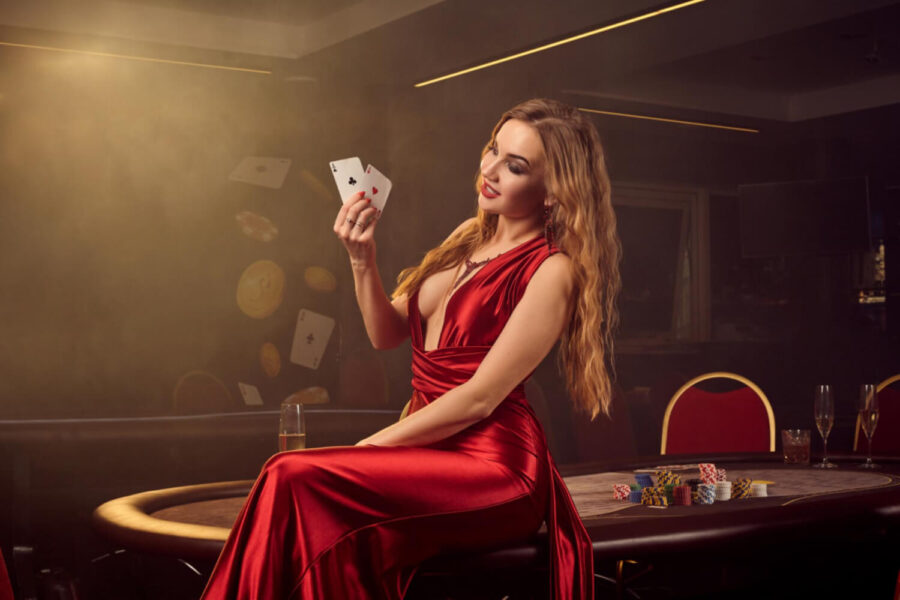 Mujer con vestido rojo en un casino sosteniendo un parde cartas