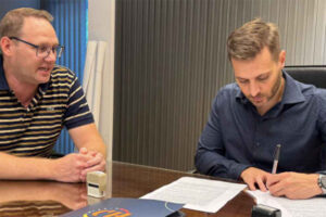 El presidente de Lotería Chaqueña, Lucas Apud Masín, y el titular del Club Social de Las Breñas, Sebastian Pertile, firman un acuerdo. Foto: Lotería Chaqueña.