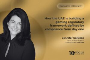A promotional graphic for an ‘Exclusive Interview’ with Jennifer Carleton, Chief of Licensing and Investigations at GCGRA. The design features a black-and-white portrait of a smiling Carleton on the left, set against a smooth, golden gradient background. On the right, the main headline reads, ‘How the UAE is building a gaming regulatory framework defined by compliance from day one’. The Focus Gaming News logo is positioned in the bottom-right corner.