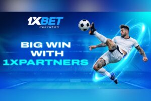 A promotional graphic for 1xBet Partners featuring a football player in a white kit performing a dynamic mid-air volley. The player is encircled by glowing blue energy trails against a blue-tinted stadium background. The bold text in the centre reads ‘BIG WIN WITH 1XPARTNERS’, with the company logo positioned at the top.