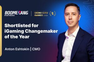A promotional graphic from Boomerang Partners announcing that Anton Eshtokin, CMO, has been ‘Shortlisted for iGaming Changemaker of the Year’ at the Casino Guru Awards 2026. The image features a professional portrait of Eshtokin on the right, wearing a dark blue suit and white shirt, against a navy and bright blue textured background. The Boomerang Partners and Casino Guru Awards logos are displayed at the top.