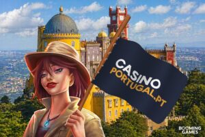 A promotional graphic for Booming Games celebrating its partnership with Casino Portugal. In the foreground, an illustrated female explorer with red hair and a tan fedora holds a dark blue flag displaying the text ‘CASINO PORTUGAL.PT’. The background features the colourful towers of the Pena Palace in Sintra, Portugal, overlooking a lush green landscape. The Booming Games logo is positioned in the bottom-right corner.