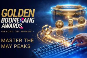 A promotional graphic for the Golden Boomerang Awards 2026. The design features a sleek, 3D golden boomerang trophy standing upright against a dark navy blue background filled with sparkling golden dust and light particles. The words ‘GOLDEN BOOMERANG AWARDS 2026’ are prominently displayed in elegant gold and white lettering.