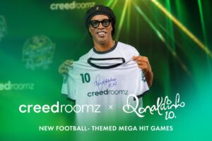 The image shows former football player Ronaldinho holding a t-shirt with his signature and the logo of CreedRoomz. There's a text that reads: New football themed mega hit games. Creedroomz + Ronaldinho.