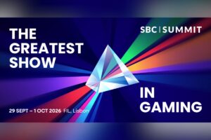 A promotional event graphic for SBC Summit set against a dark blue background with dynamic, multi-coloured light rays radiating outwards from the centre. In the middle sits a large, transparent 3D glass prism that refracts the light into vibrant beams of red, orange, green, purple, and blue. On the left side, the text reads ‘THE GREATEST SHOW IN GAMING’. The white SBC Summit logo is positioned in the top-right corner, and the event details are displayed at the bottom left: ‘29 SEPT – 1 OCT 2026, FIL, Lisbon’.