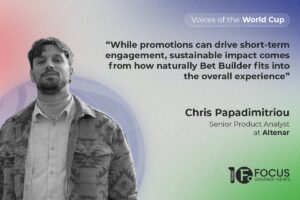 A promotional feature graphic for the ‘Voices of the World Cup’ series by Focus Gaming News. On the left side, a black-and-white portrait shows Chris Papadimitriou, Senior Product Analyst at Altenar, looking forward whilst wearing a collared shirt under a patterned overshirt. The background features a soft, grainy gradient transitioning from pink on the left through blue to green on the right. On the upper right, a large dark grey quote reads: “While promotions can drive short-term engagement, sustainable impact comes from how naturally Bet Builder fits into the overall experience”. Papadimitriou’s name and job title are printed below the quote, a white pill-shaped graphic containing ‘Voices of the World Cup’ is in the top-right corner, and the Focus Gaming News logo is in the bottom-right corner.